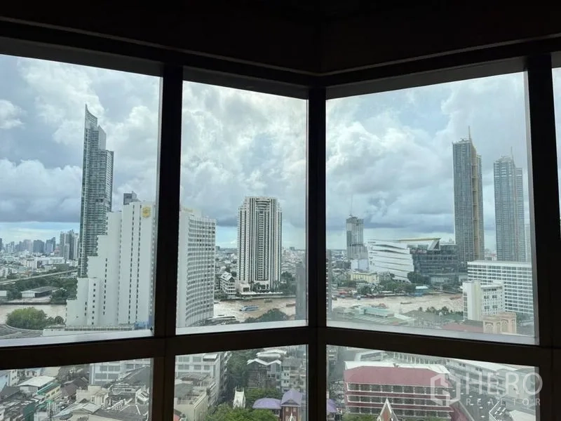 คอนโด ให้เช่าในBang Rak, Bangkok - มุมมองสกายไลน์และแม่น้ำแบบพาโนรามาจากหน้าต่างมุมในวันที่มีเมฆ