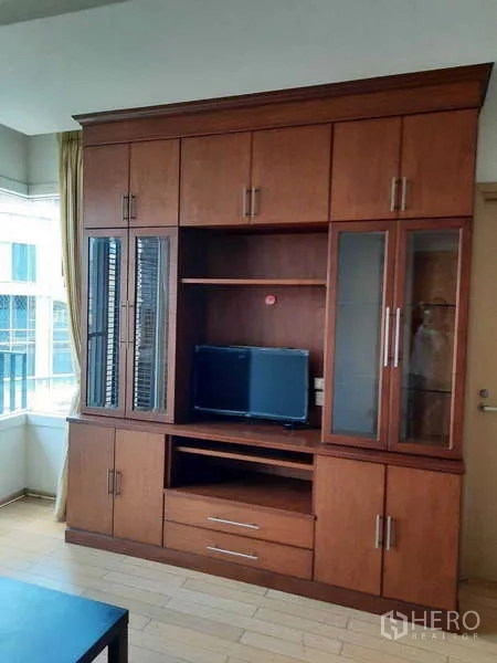Condominium for rent in Khlong Toei, Bangkok - Tall built-in wooden entertainment cabinet with glass doors.