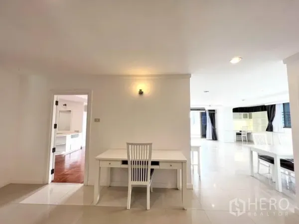 公寓 出租在Watthana, Bangkok - 开放式空间，浅色地砖、白色书桌，门口通往木地板房间。