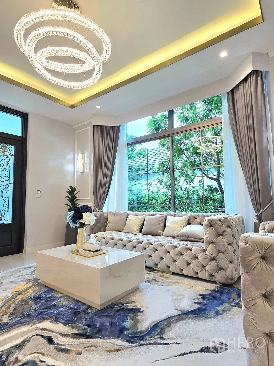 บ้านเดี่ยว for rent or sale in Bang Phli, Samut Prakan - ห้องนั่งเล่นหรู โซฟาหนังปุ่มคริสตัล โคมระย้าวงแหวน โต๊ะกลางหินอ่อน และหน้าต่างชมสวน