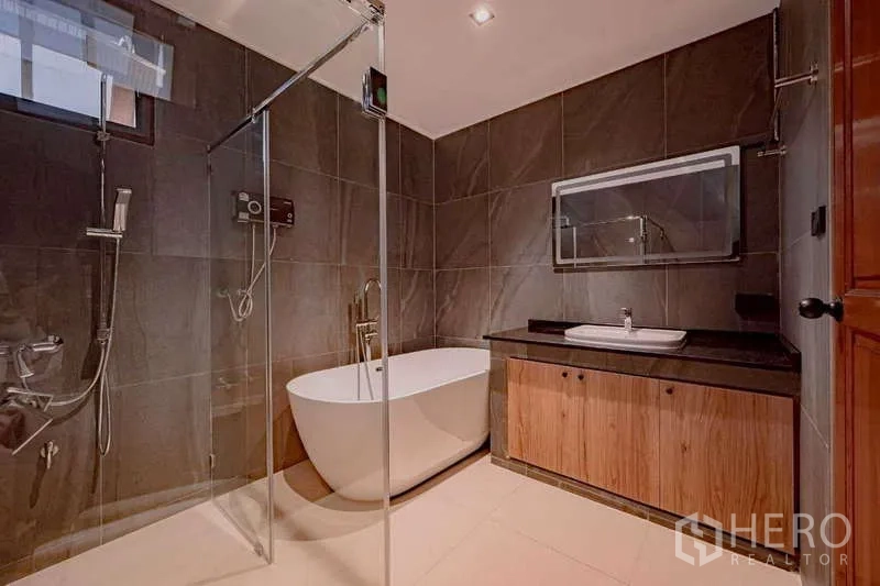 Detached House for rent or sale in Phra Khanong, Bangkok - Modern bathroom featuring a freestanding bathtub, glass shower, and stone vanity.