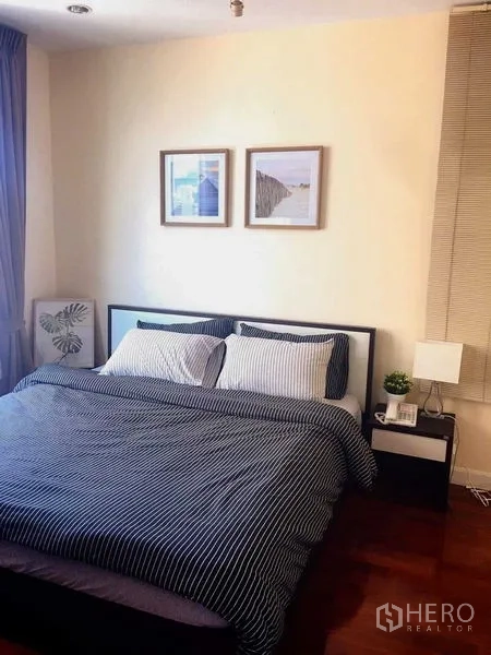 Condominium for rent in Khlong Toei, Bangkok - Cozy bedroom with double bed, side tables, and framed wall art.