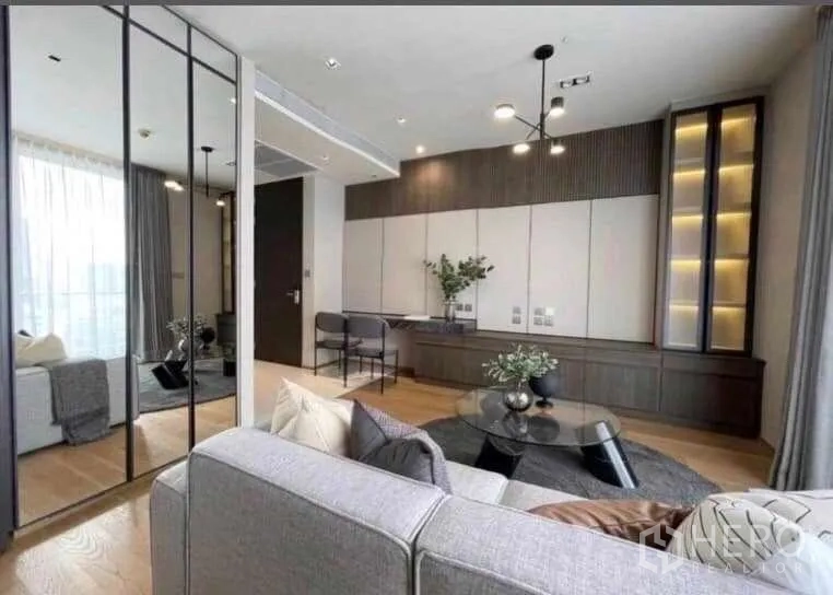 Condominium for rent or sale - Living room with mirrored wall panels and illuminated display shelving.