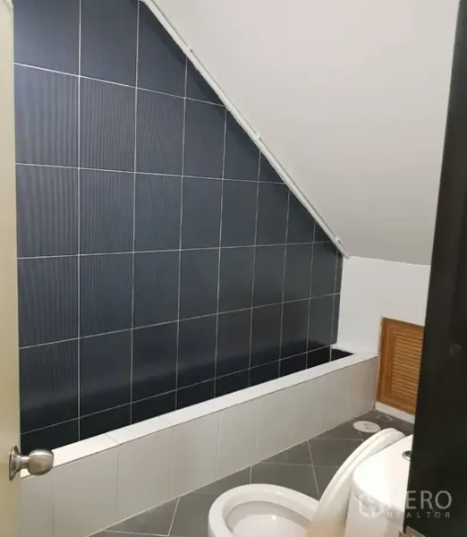 Shophouse for rent in Watthana, Bangkok - Bathroom with sloped ceiling, dark tiled wall and built-in bathtub.