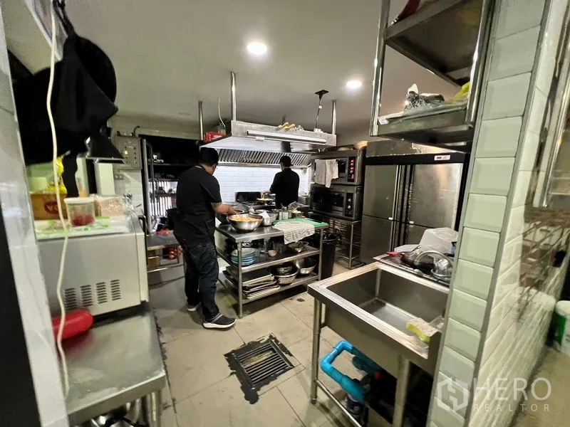 Shophouse for rent in Watthana, Bangkok - Commercial kitchen with stainless appliances, ventilation hood, refrigerators, and worktables.