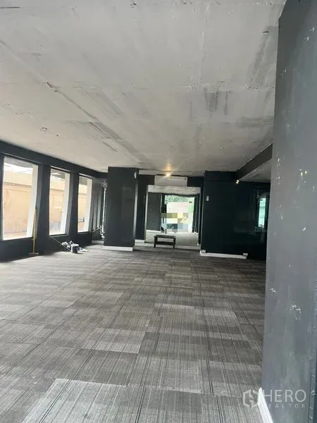 Retail Space for rent in Watthana, Bangkok - Open‑plan retail interior with carpet tiles, dark columns and floor‑to‑ceiling windows providing natural light.