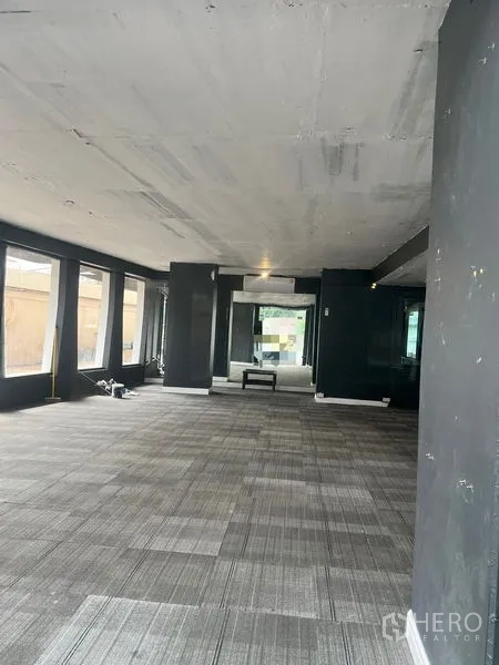 Retail Space for rent in Watthana, Bangkok - Open‑plan retail interior with carpet tiles, dark columns and floor‑to‑ceiling windows providing natural light.