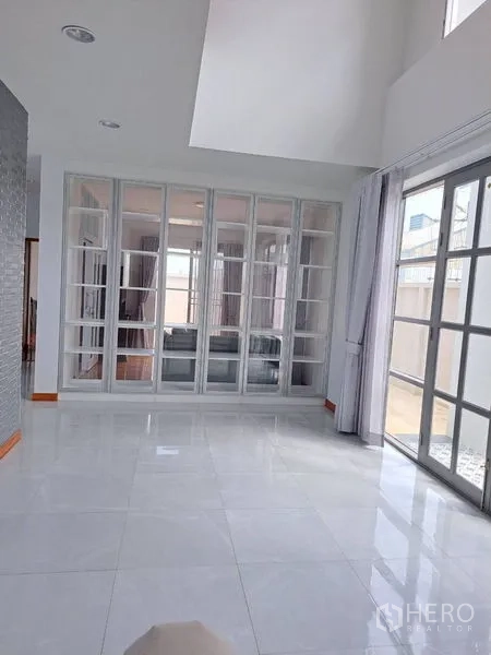 独立式住宅 出租在Prawet, Bangkok - 明亮客厅，白色地砖，整面玻璃隔断与推拉门。