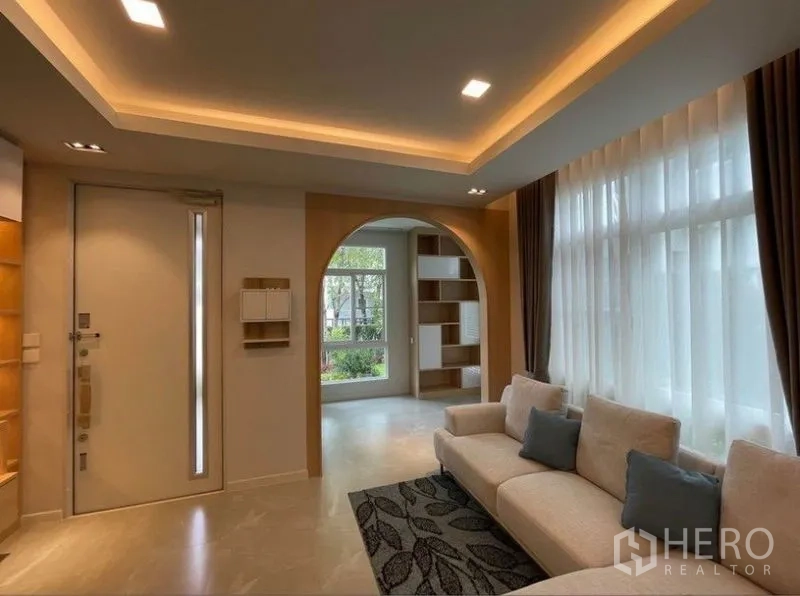 独立式住宅 出租在Prawet, Bangkok - 曼谷帕威区独栋住宅明亮客厅，吊顶氛围灯、大窗与拱形通道。