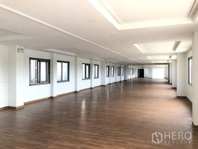 Factory for rent or sale in Samut Prakan - Large open-plan office floor with wood-look flooring and rows of windows.