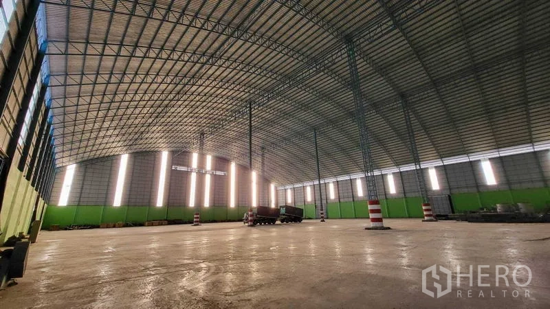 โรงงาน ให้เช่าในSai Noi, Nonthaburi - ภาพพาโนรามาฮอลล์ผลิตกว้าง โครงหลังคาเหล็กและเสาแถบสีขาวแดง