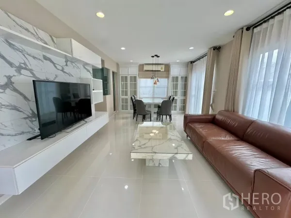 บ้าน ให้เช่าในBang Phli, Samut Prakan - ห้องนั่งเล่นโปร่งโล่ง ผนังทีวีลายหินอ่อน โซฟาหนัง และหน้าต่างบานใหญ่