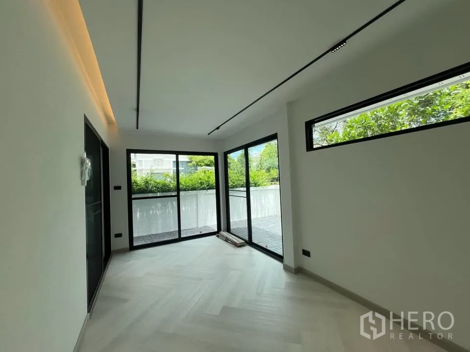 联排别墅 for rent in Prawet, Bangkok - 一层房间，大幅推拉玻璃门通向露台。