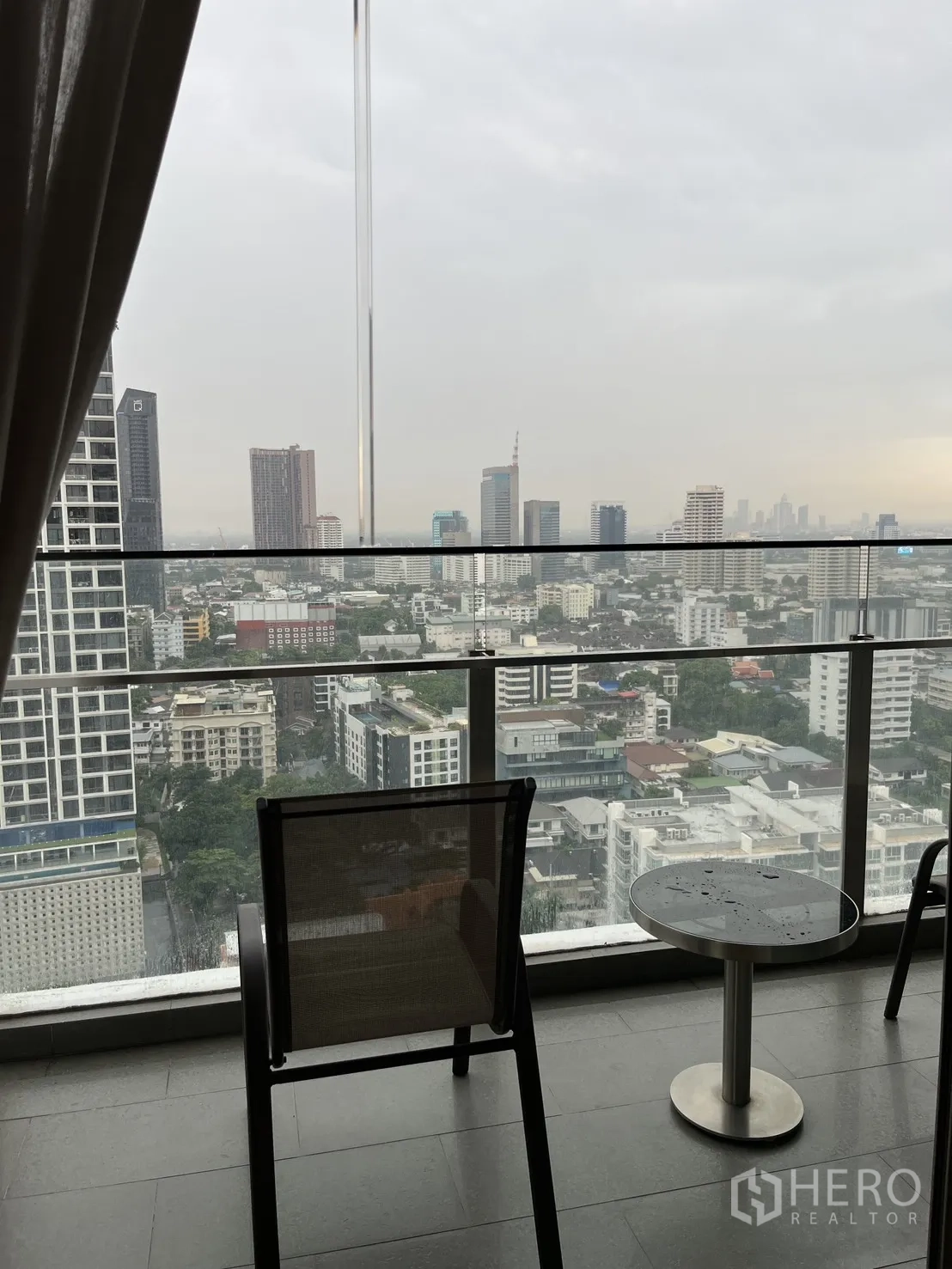 Condominium for rent in Watthana, Bangkok - Private balcony with chairs and a small table facing a panoramic city skyline.
