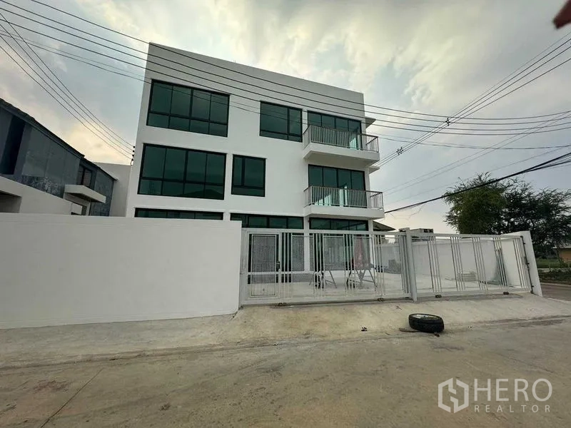 Home Office for rent in Don Mueang, Bangkok - Modern three-storey home office with large tinted windows, balconies and a gated parking forecourt.