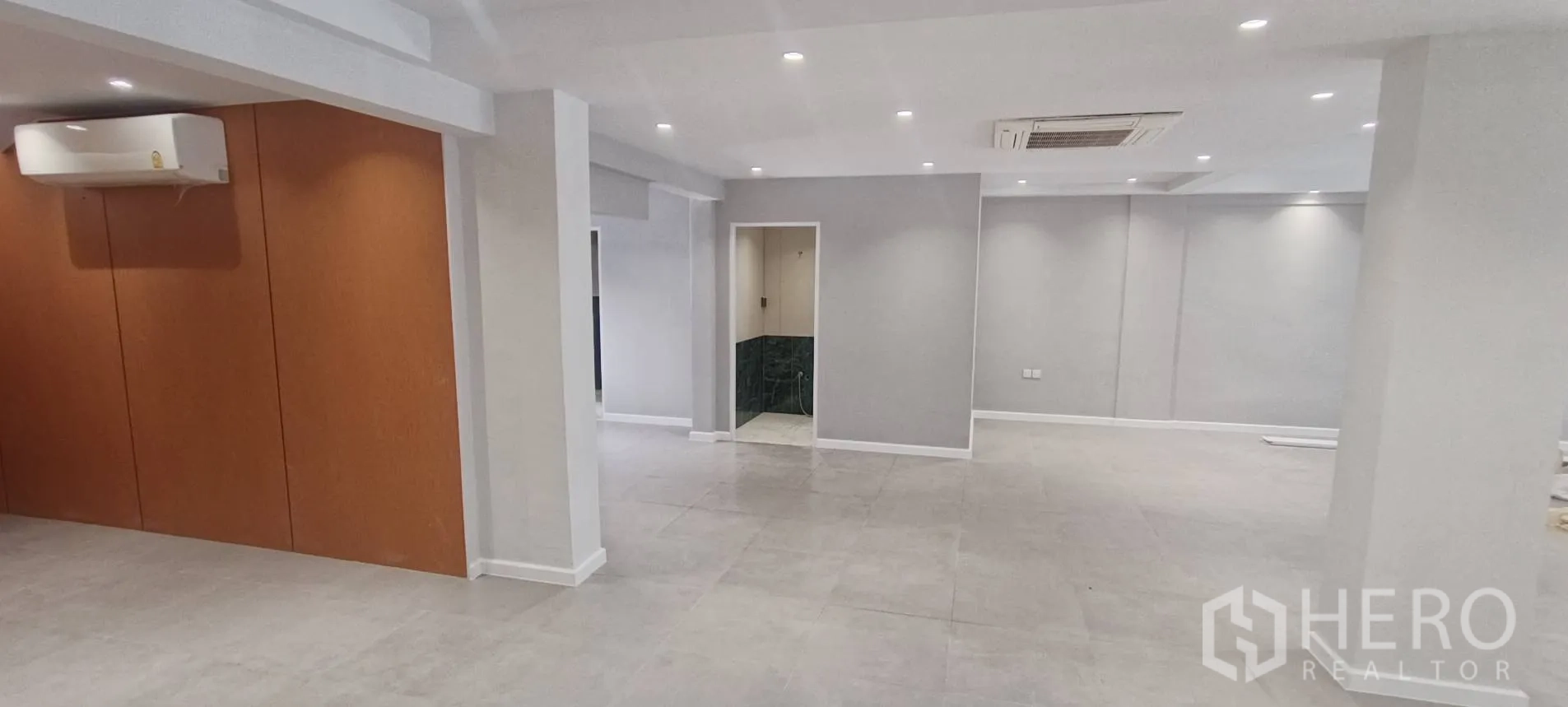 Office Space for rent in Watthana, Bangkok - Open workspace showing doorway to a restroom and wood accent panels.