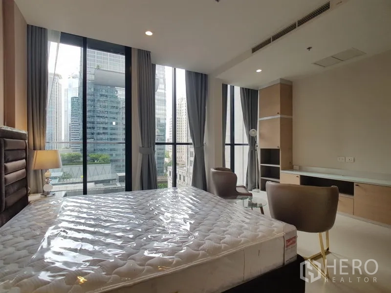 公寓 出租在Pathum Wan, Bangkok - 卧室带全景落地窗与内置书桌，俯瞰曼谷天际线