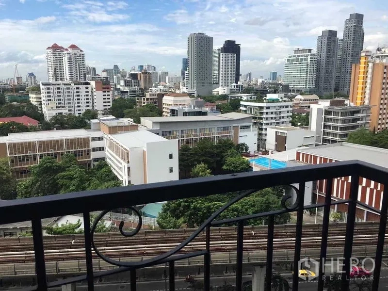 Condominium for rent in Khlong Toei, Bangkok - Balcony view of the Sukhumvit city skyline with BTS tracks and mid-rise buildings.
