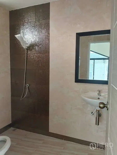 工厂 出租或出售在Sai Noi, Nonthaburi - 厂区卫生间，设淋浴区、棕色特色墙砖与壁挂式洗手盆。