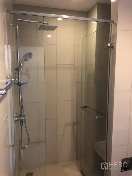 Condominium for rent in Watthana, Bangkok - Modern bathroom with glass-enclosed rain shower and handheld shower set.
