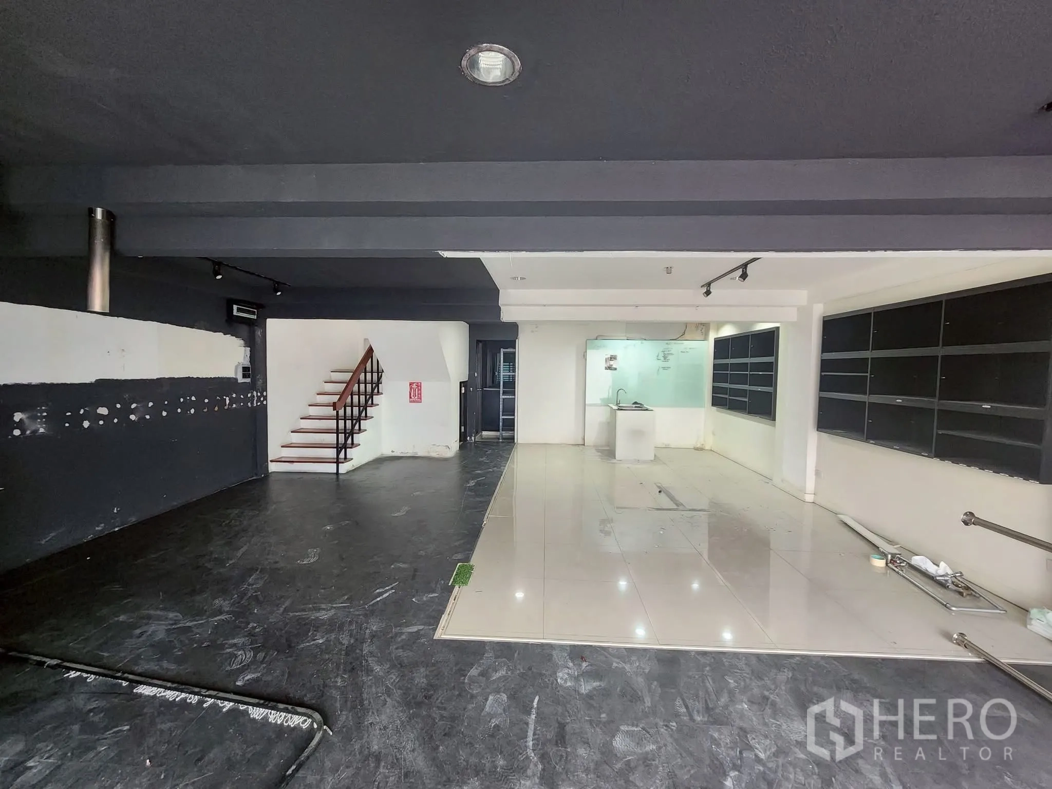 家庭办公室 for rent in Khlong Toei, Bangkok - 开放式展厅空间，轨道射灯、墙面展示架及通往楼上的楼梯。