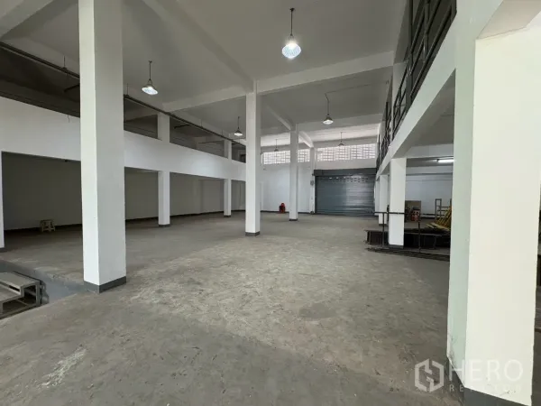 Warehouse for rent in Bang Na, Bangkok - Open interior facing multiple roller shutters and an entrance canopy.
