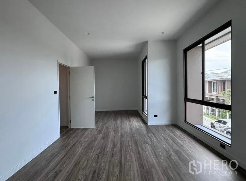 Detached House for rent in Bang Kapi, Bangkok - Upper-floor bedroom with wood floors and large picture windows.