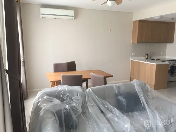 公寓 出租在Ratchathewi, Bangkok - 开放式起居区，餐桌紧邻浅木色橱柜的紧凑厨房并配空调。