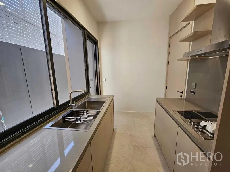 Detached House for rent in Wang Thonglang, Bangkok - Sleek Western kitchen with long countertops, sink, and cooktop by the window.