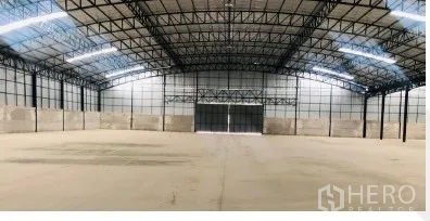 Warehouse for rent in Chon Buri - Open-plan warehouse interior featuring a high steel-truss roof, skylights, and large sliding doors.