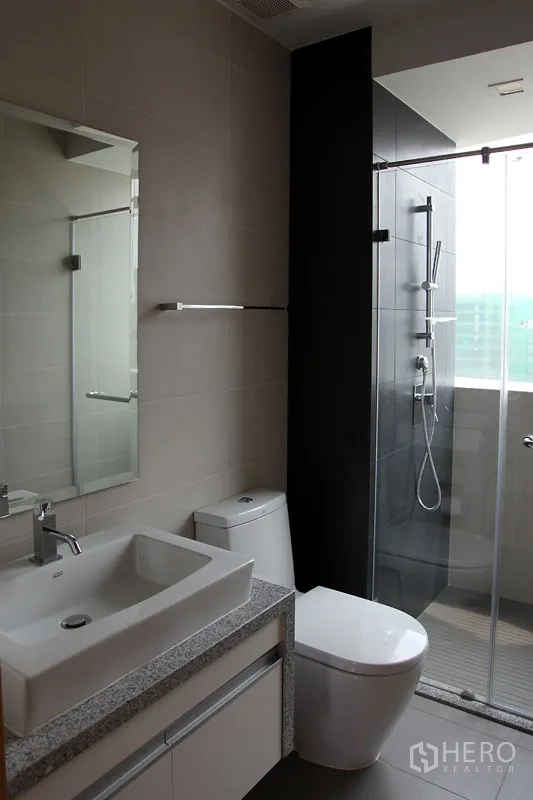 Condominium for rent in Khlong Toei, Bangkok - Modern bathroom featuring square basin, stone vanity, toilet and glass-enclosed shower.