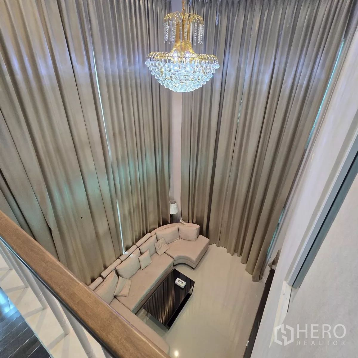 Detached House for rent in Mueang Pathum Thani, Pathum Thani - View over the double-height living room with chandelier and full-length curtains.