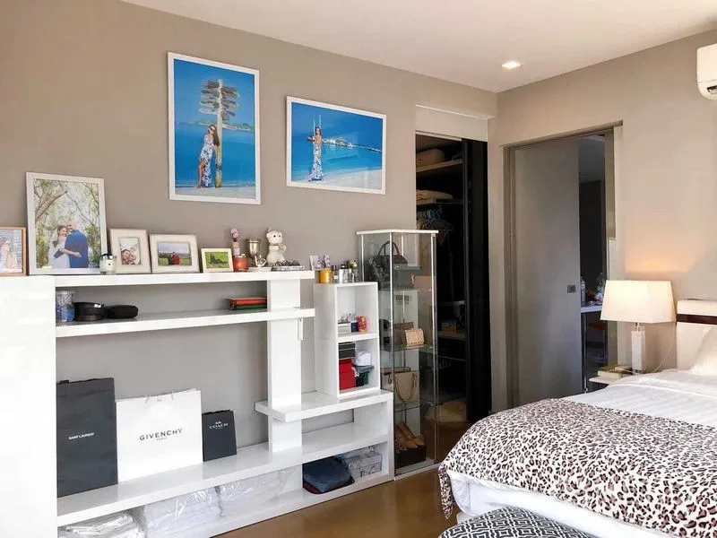 Condominium for rent in Bang Rak, Bangkok - Bedroom with shelving and walk-in closet adjacent to the bed.