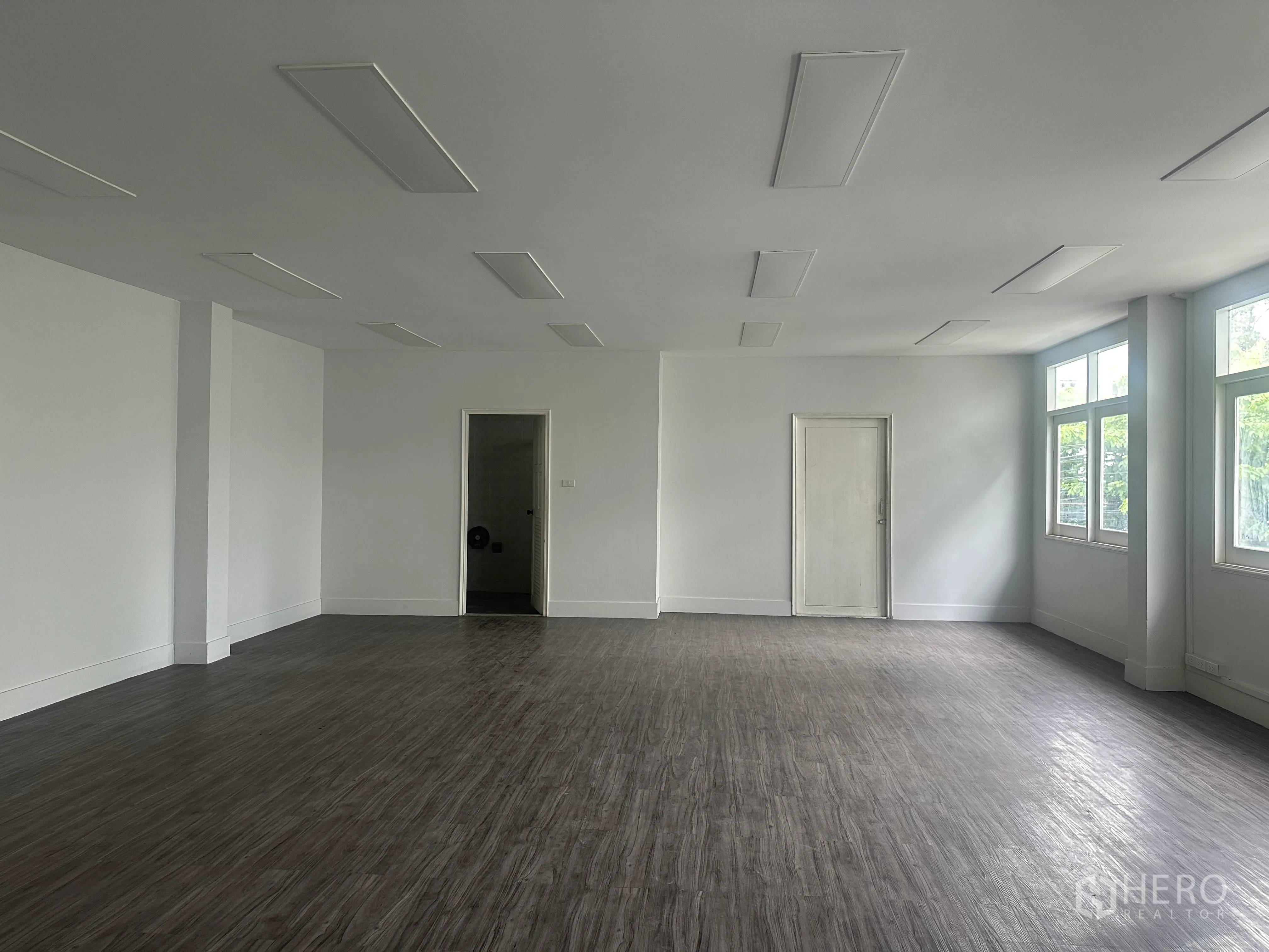 Retail Space for rent in Bang Rak, Bangkok - Spacious open-plan room with wood-look flooring and windows.