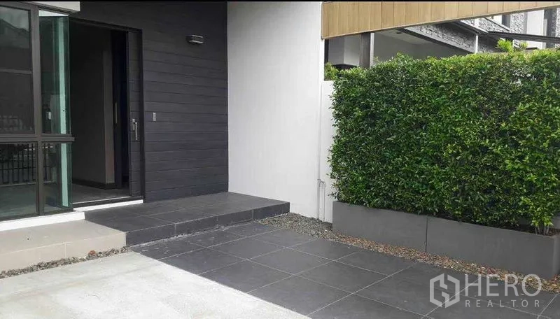 Townhouse for rent - Front patio with gray tiles, hedge for privacy, and sliding glass entry to the townhouse.
