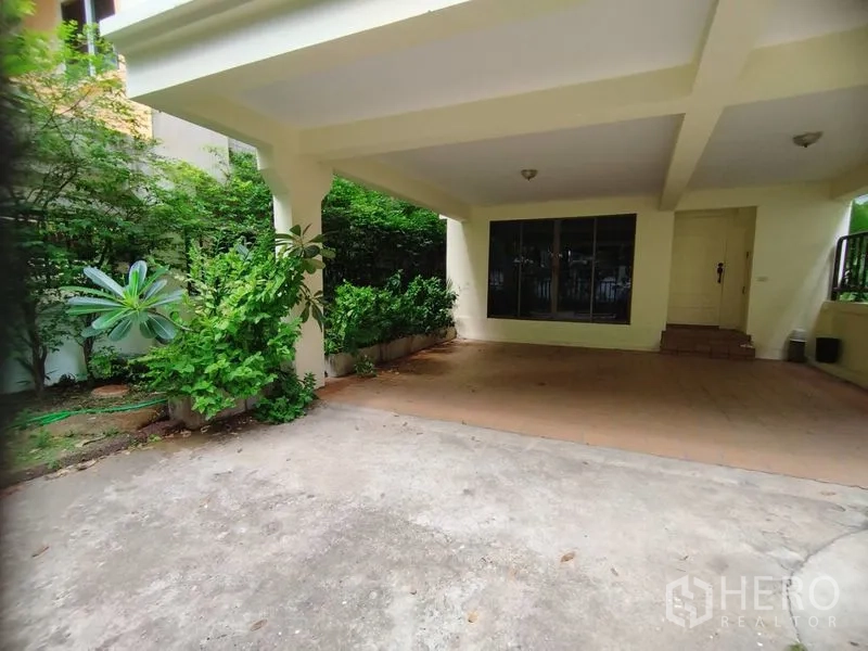 Detached House for rent in Watthana, Bangkok - Covered carport and entryway framed by greenery.