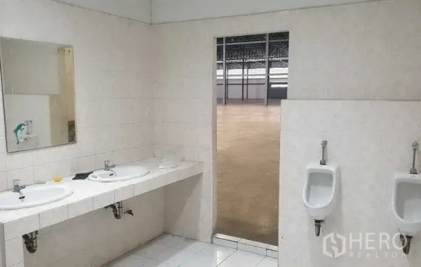 Warehouse for rent in Mueang Samut Prakan, Samut Prakan - Washbasins and urinals with tiled walls opening out to the warehouse floor.