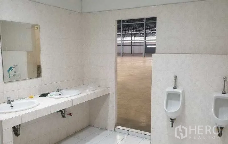 Warehouse for rent in Mueang Samut Prakan, Samut Prakan - Washbasins and urinals with tiled walls opening out to the warehouse floor.