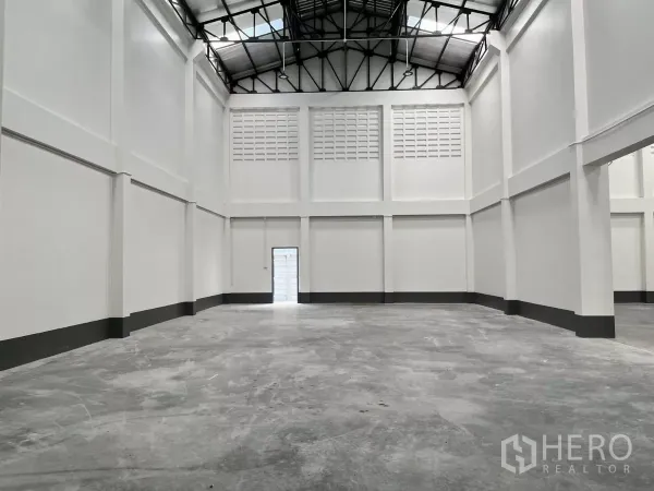 Warehouse for rent in Mueang Samut Sakhon, Samut Sakhon - Empty warehouse space with tall white walls, durable concrete floor, side door and insulated steel roof.