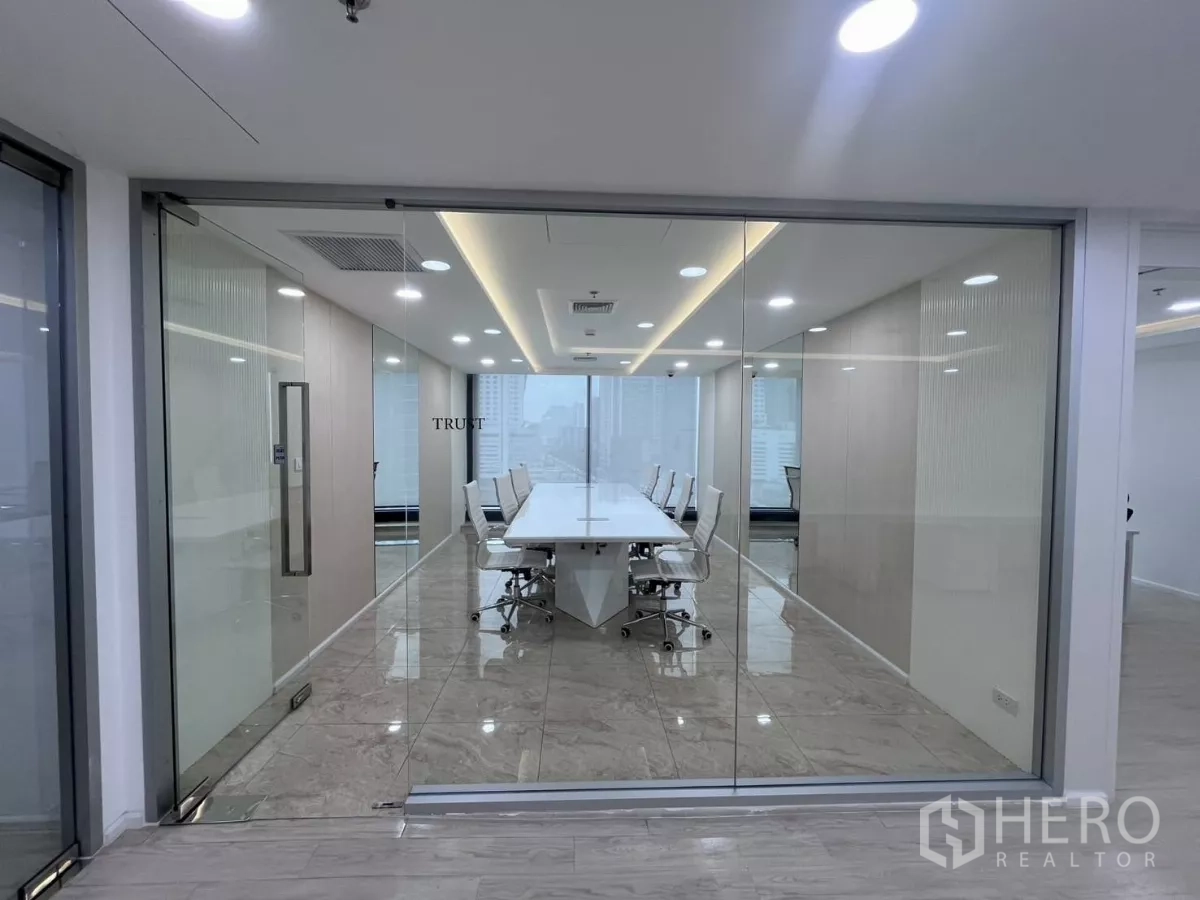 办公空间 出租在Din Daeng, Bangkok - 玻璃隔断会议室，长条白色会议桌，大理石地面与LED照明，可见城市景观。
