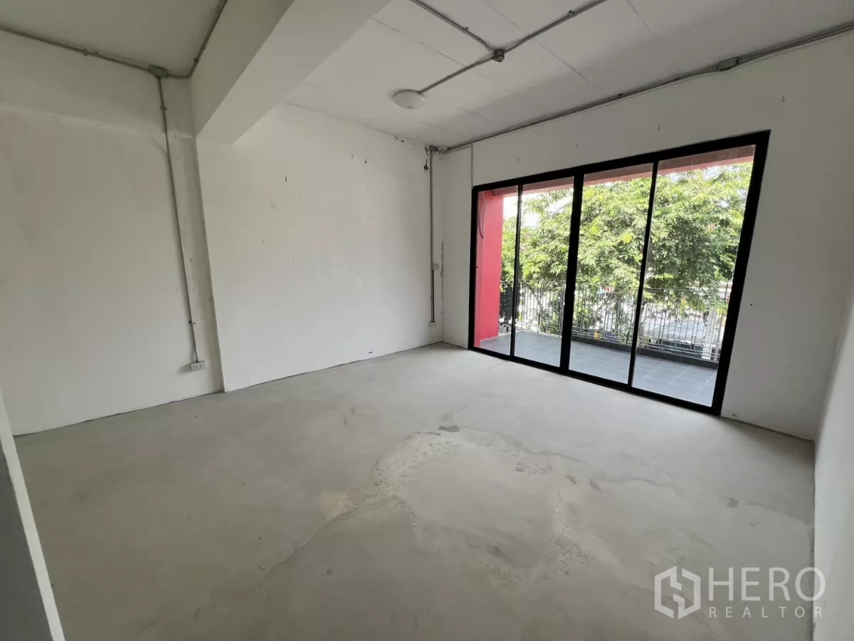 Retail Space for rent in Khlong Toei, Bangkok - Bright white room opening to a balcony via large sliding doors facing greenery.