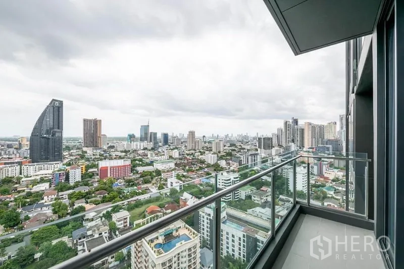 公寓 出租在Pathum Wan, Bangkok - 高楼阳台，玻璃护栏俯瞰曼谷天际线。