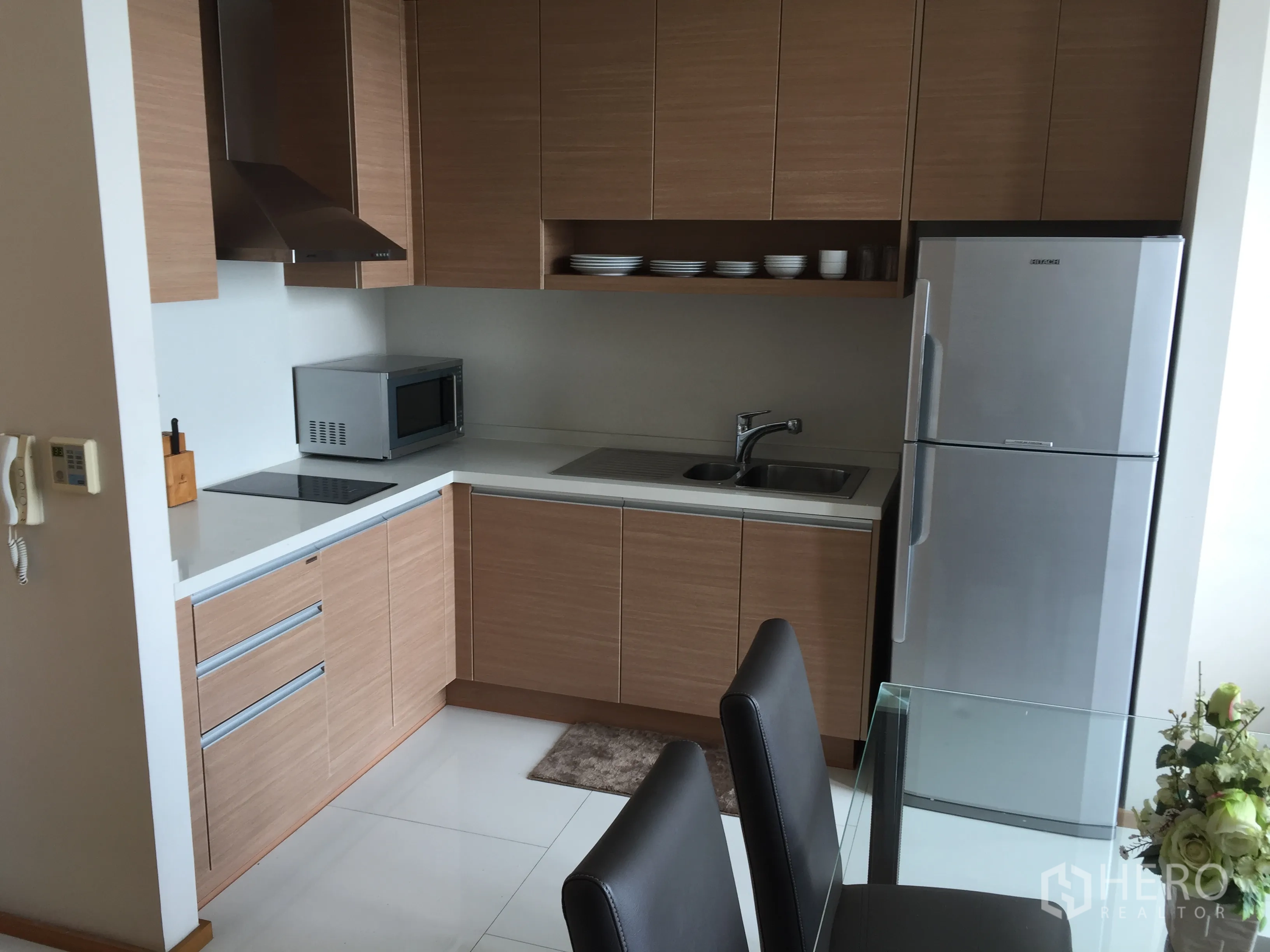 Condominium for rent in Khlong Toei, Bangkok - Modern built-in kitchen with appliances, glass dining table and ample storage.