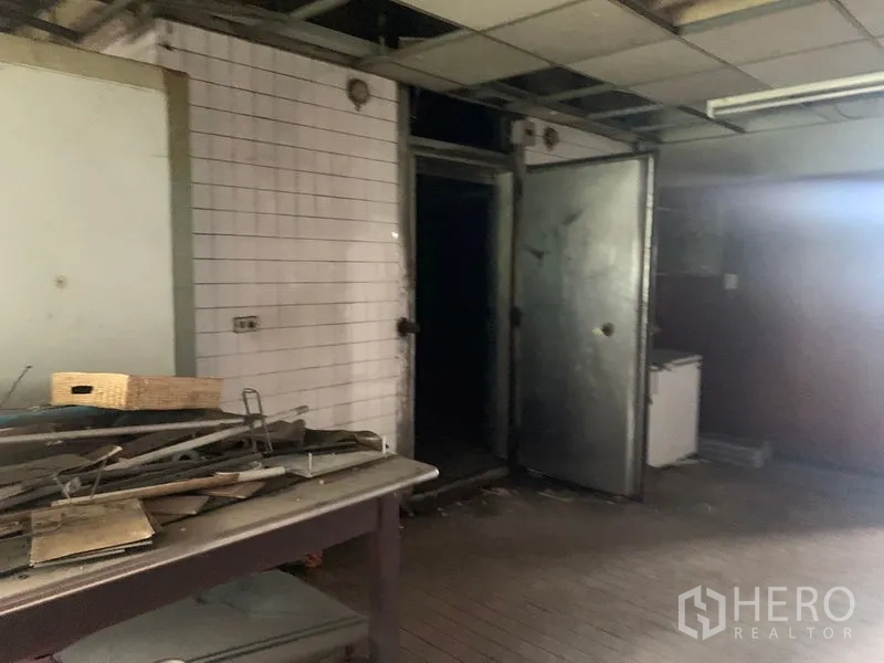 Shophouse for rent in Watthana, Bangkok - Back-of-house prep room with white tiled walls, metal doors and worktable.