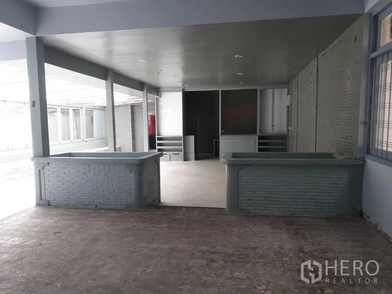 Detached House for rent in Watthana, Bangkok - Shaded open hall with brick half-walls and concrete flooring.