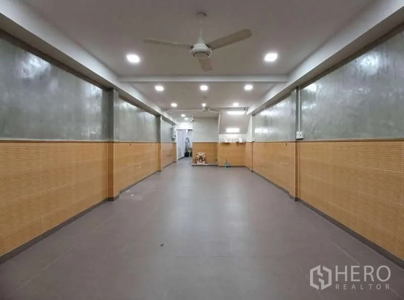 Shophouse for rent in Phra Khanong, Bangkok - Long ground-floor commercial hall with tiled floor, ceiling fans and downlights, ready for retail or office use.