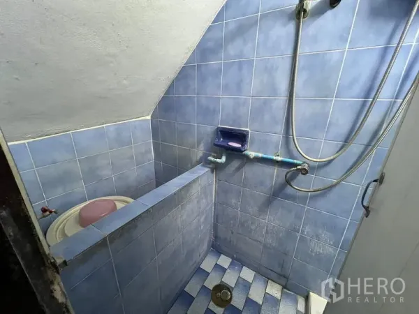 Shophouse for sale in Phra Khanong, Bangkok - Compact blue‑tiled bathroom with handheld shower under a sloped ceiling.