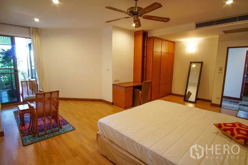 Apartment for rent in Watthana, Bangkok - Another angle of the large bedroom showing built-in storage, study space, and balcony door.