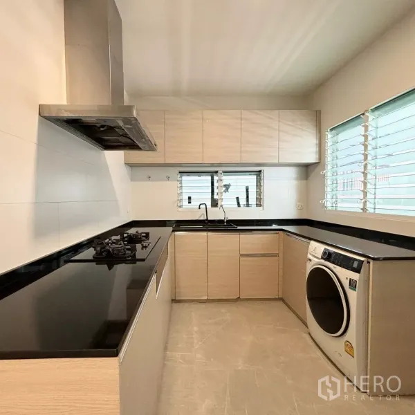 Detached House for rent or sale in Prawet, Bangkok - Separate Thai kitchen with black stone counters, gas hob, stainless hood and window ventilation.