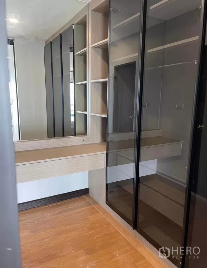 Condominium for rent in Sathon, Bangkok - Walk-in closet with glass-front wardrobes, shelving, and vanity mirror.